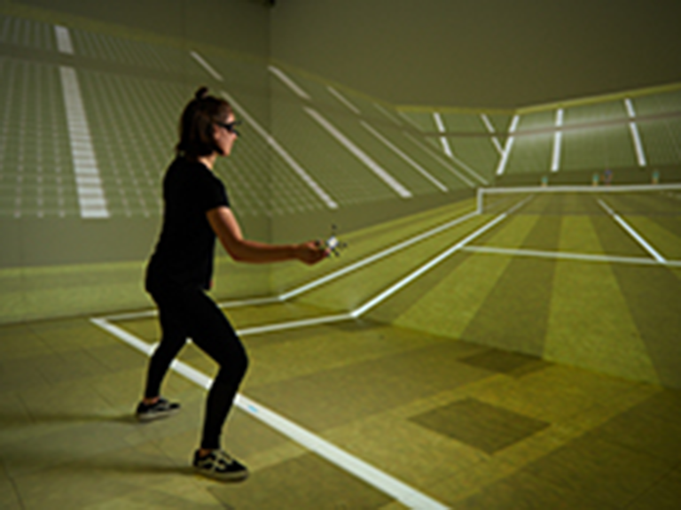 Zu sehen ist eine Frau in einem VR-Raum der aber aussieht wie ein virtueller Tennis-Platz und sie spielt virtuell